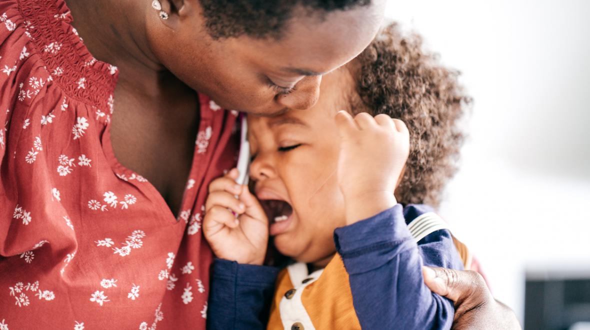 closeup of a mother kissing her tantruming screaming toddler