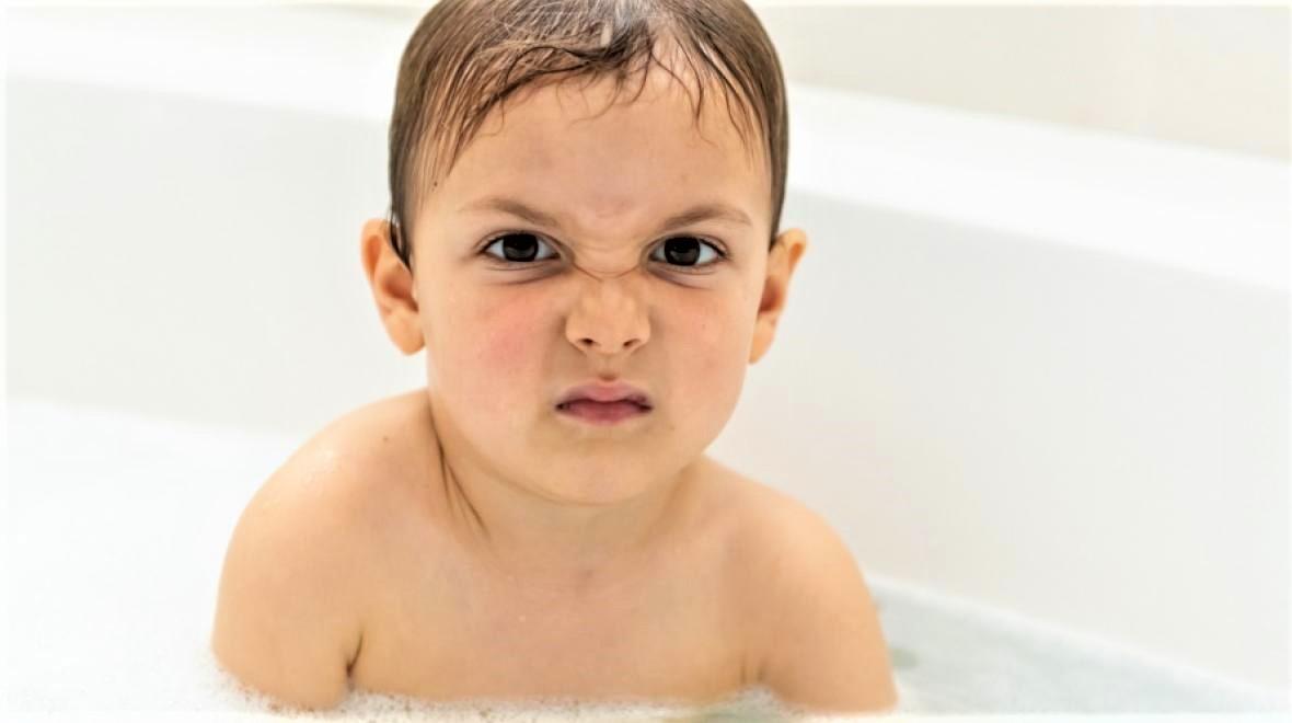 grumpy child in bathtub protesting having to take a bath how often should you bathe your kid decision tool