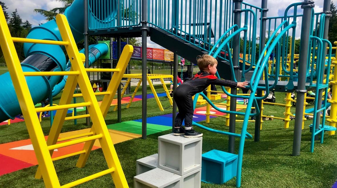 A small boy climbing the play structure at colorful new West Fenwick Park in Kent, a great destination for tots while big kids are in school