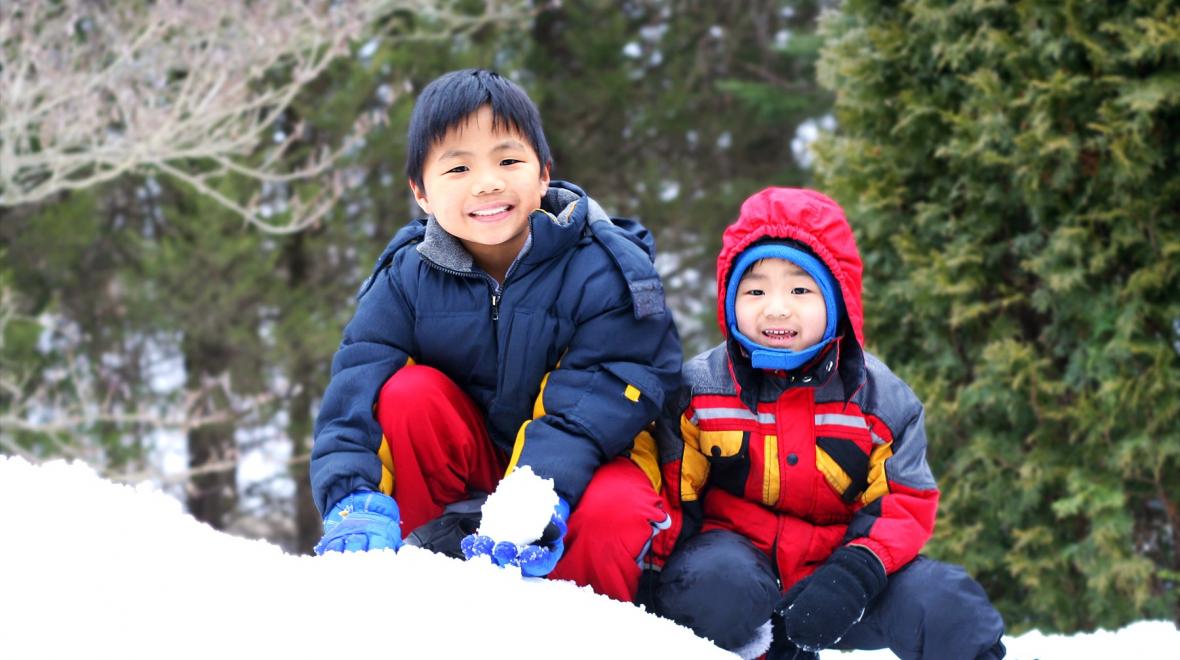 Two cute boys in jackets and hats play in the snow at Annette Lake sno park
