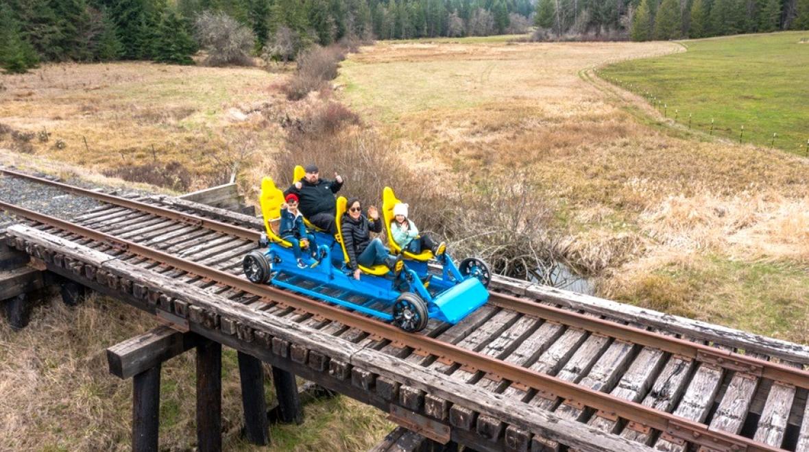 A family rides a blue rail cycle bike along the Mount Rainier Scenic Railroad tracks near Eatonville, Washington
