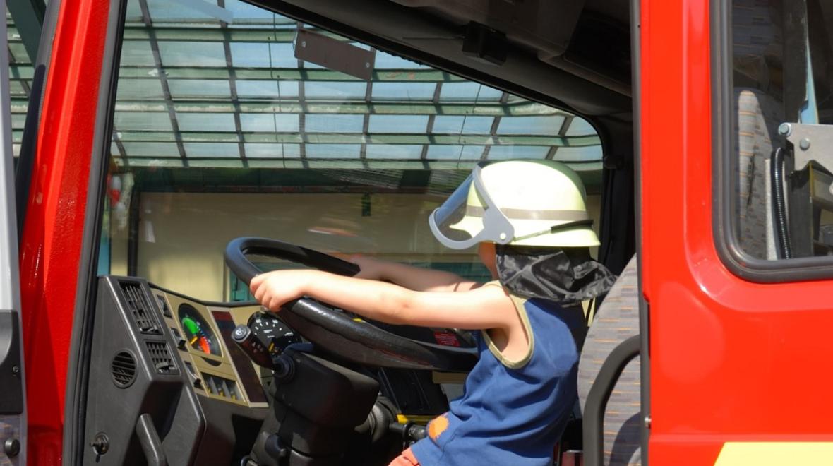 A child sits behind the wheel of a fire truck at a Seattle touch-a-truck event among family activities in Seattle for kids who love cars