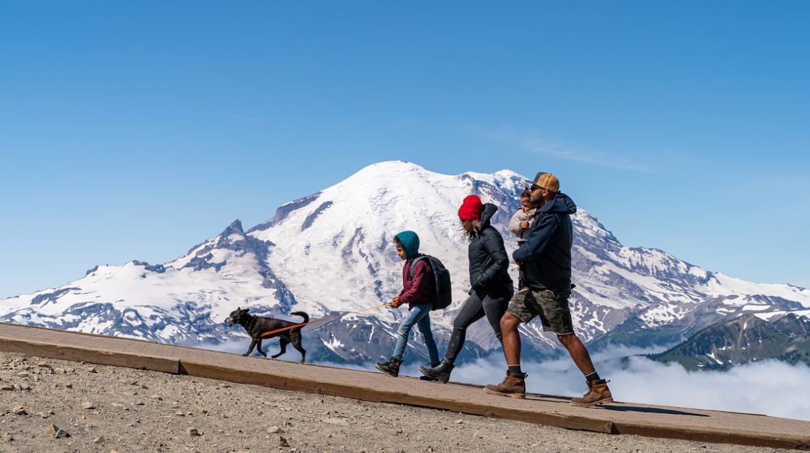Family hiking at Crystal Mountain in summer with view of Mount Rainier in the background
