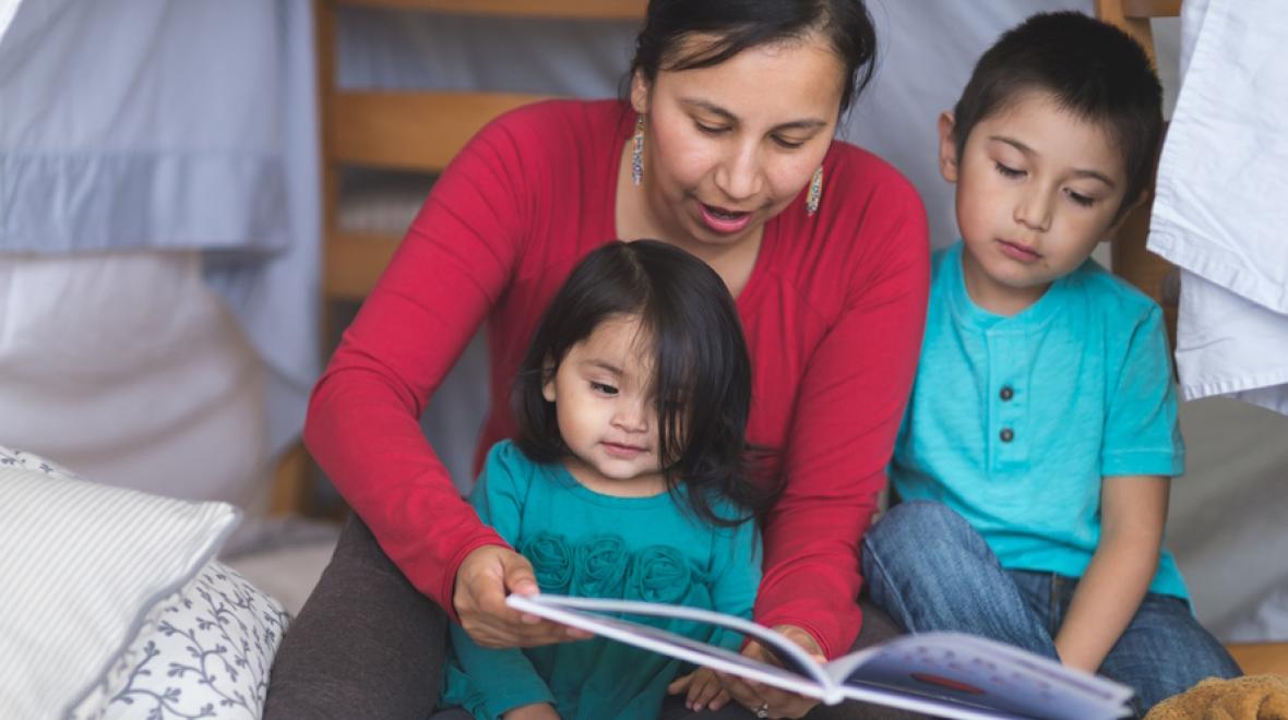 Native American mom reading books to two children