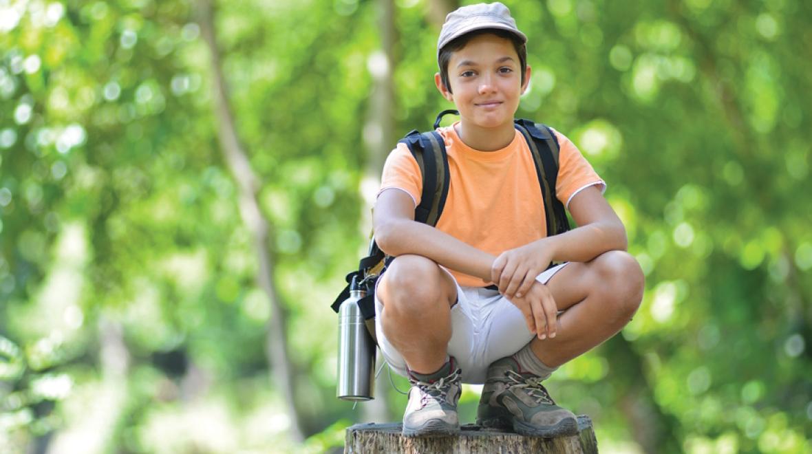 Boy sitting on a rock in the forest at a one-day or drop in Summer camp 