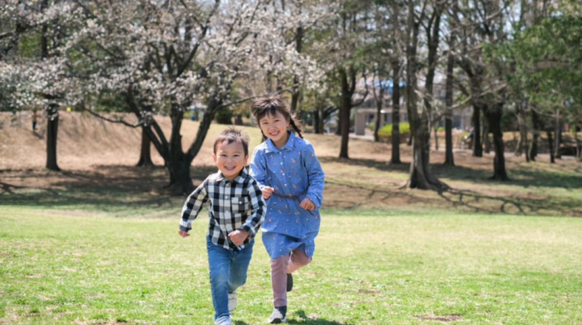 brother and sister running through cherry blossom trees during spring break