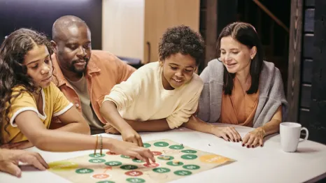 A family sitting at a table playing a board game on a family game night