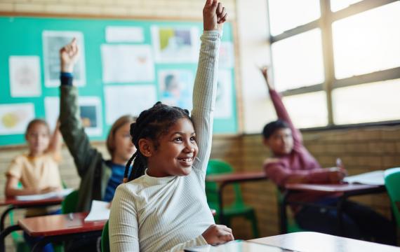 happy girl raising hand in class