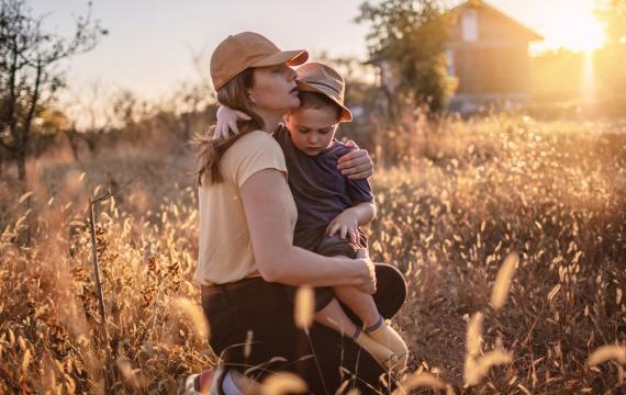 mom holding her son in a wheat field at sunset pregnancy loss