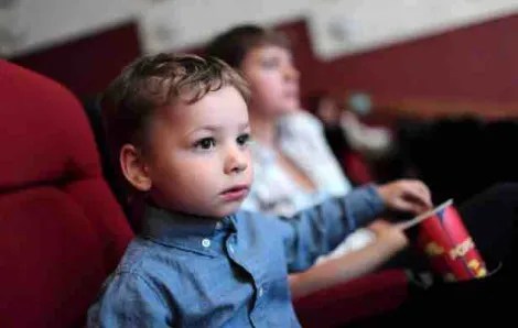Toddler boy eating popcorn in a movie theater