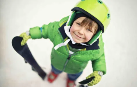 Smiling boy with skis in the snow