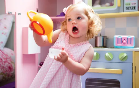 Preschool girl playing in kitchen