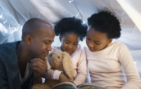 father reading to daughters at bedtime