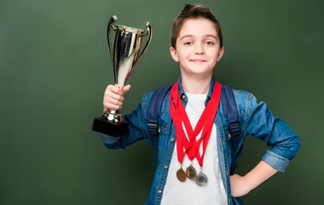 boy holding a trophy with gold medals around his neck