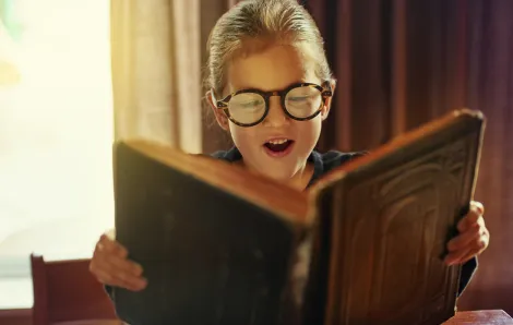 Young boy wearing glasses reads a fantasy book series