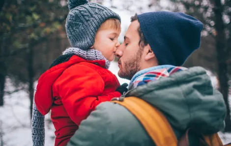 boy kissing his father's nose outside in the snowy woods