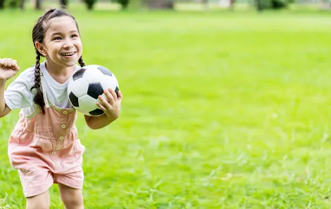 Young girl holding a soccer in a celebratory pose