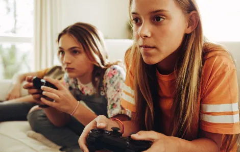 Two girls playing video games on a couch