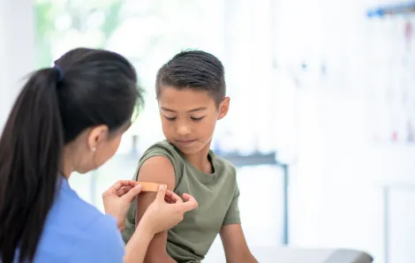 Young boy getting a shot and looking down at his arm