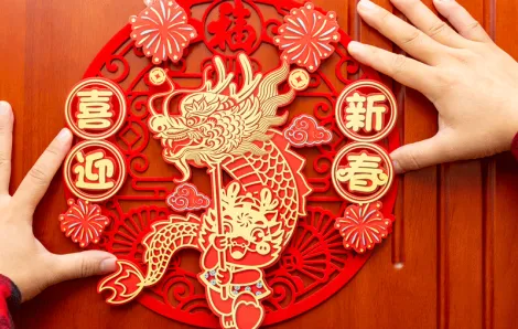 A man places a Chinese zodiac year of the dragon for kids symbol on a red door