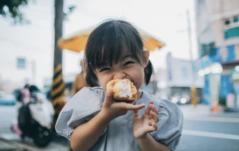 Little girl is very happy to eat cream puffs