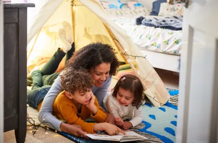 Mom reading with two kids on the floor of their bedroom Passover books