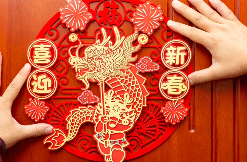 A man places a Chinese zodiac year of the dragon for kids symbol on a red door