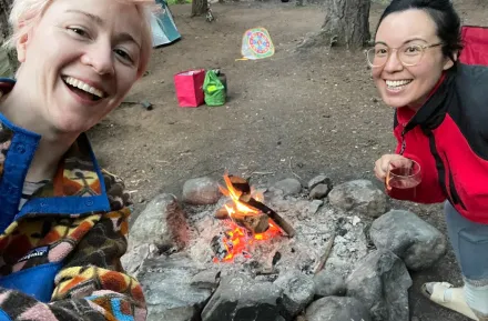 Two mom friends smile for a selfie while camping.