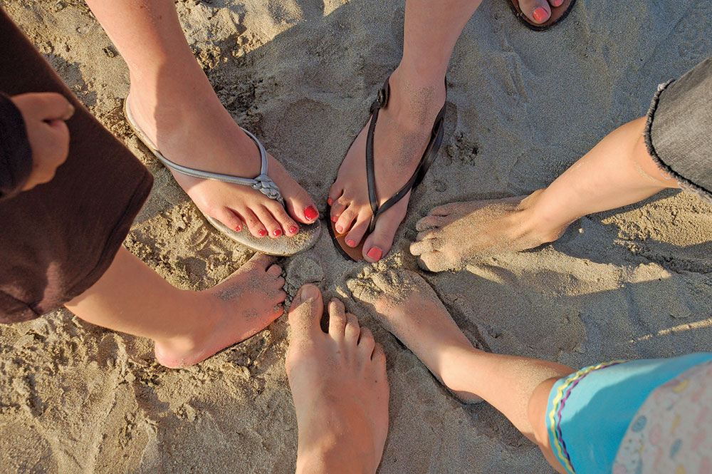 Natalie's family feet together on the sand at the beach