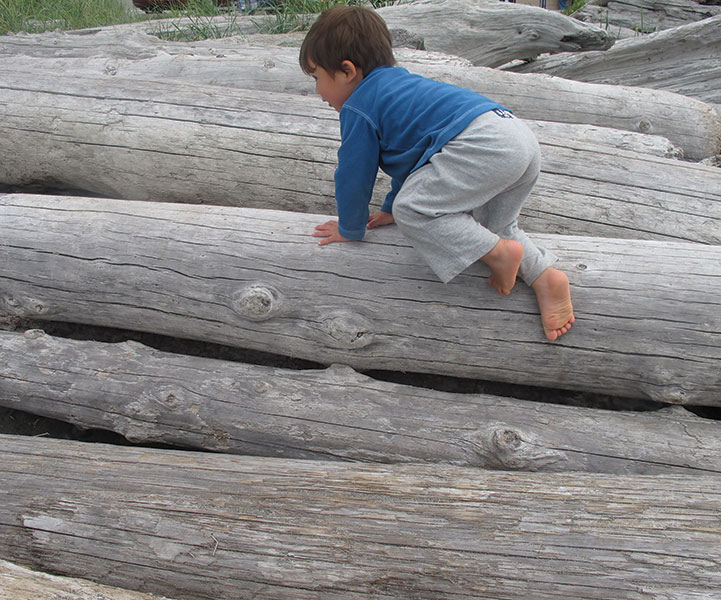 Getting Kids in Nature: Boy playing on logs at the beach