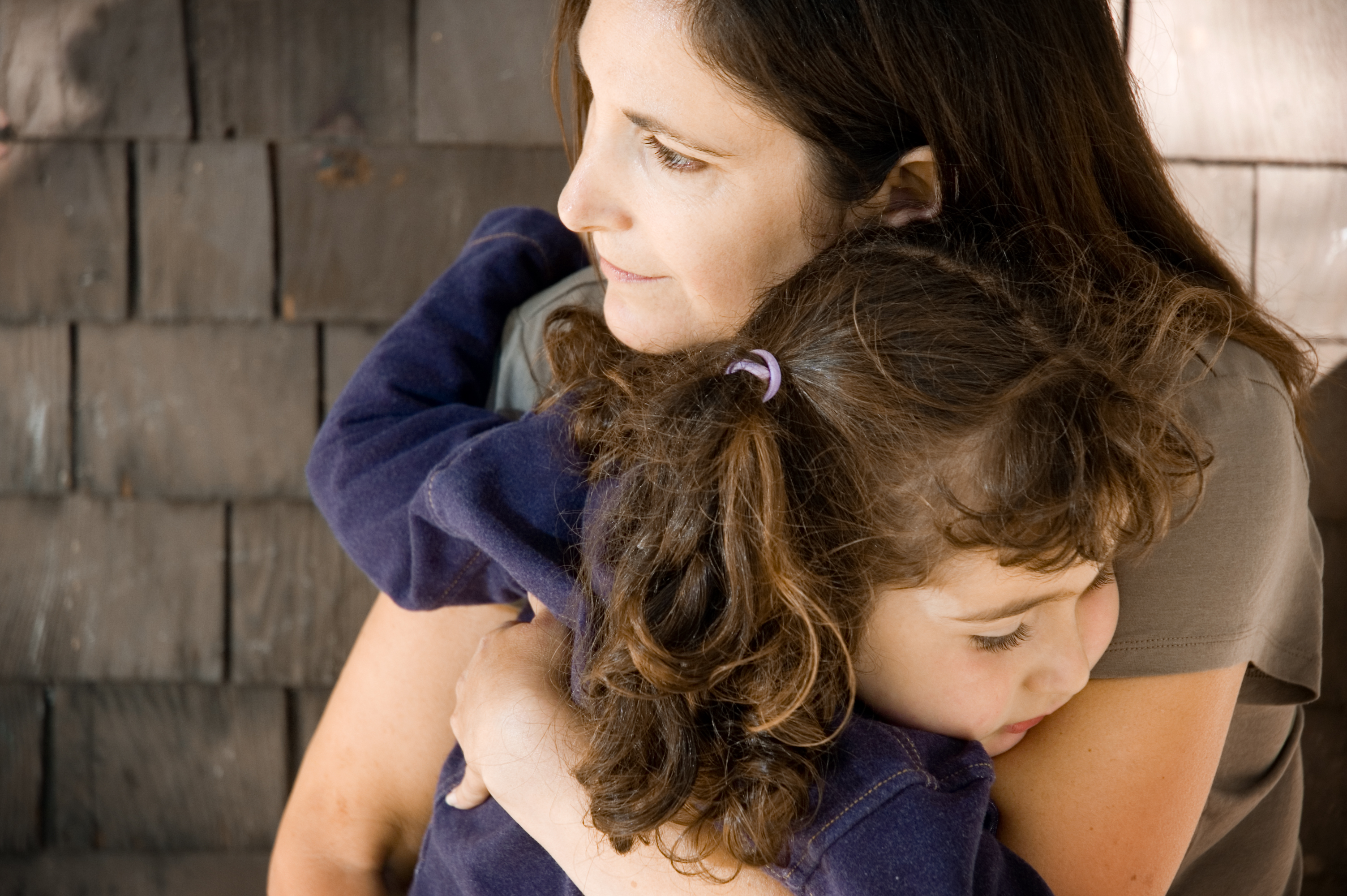 Mother hugs young female child