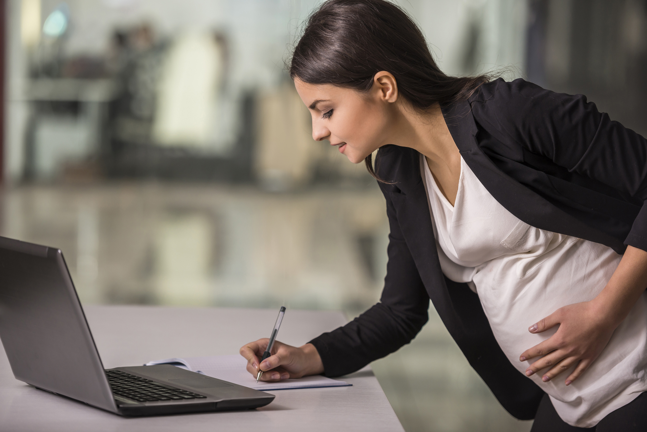 Pregnant businesswoman signs a piece of paper