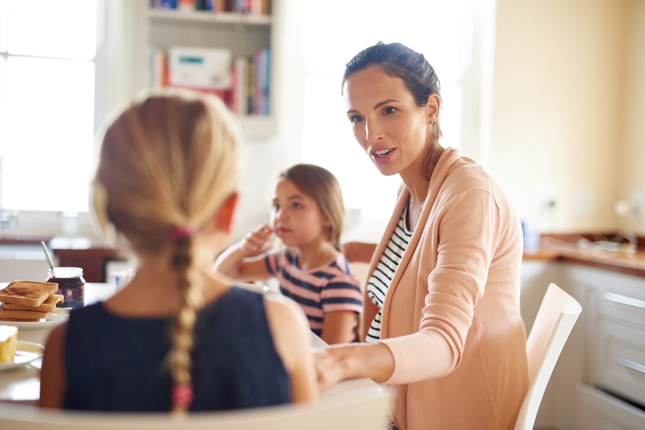 Mother and two young girls sitting around dining room table