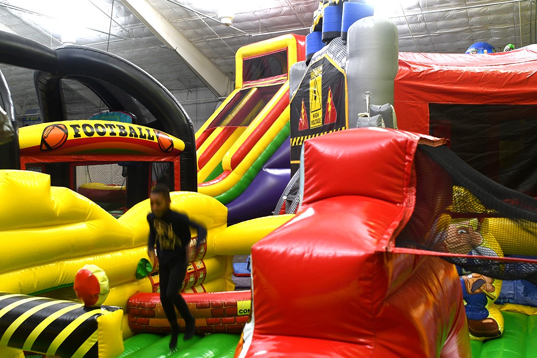 Kids play on inflatables or bouncy house toys in the fun zone at Arena Sports’ new family entertainment center in Issaquah, Wash., near Seattle