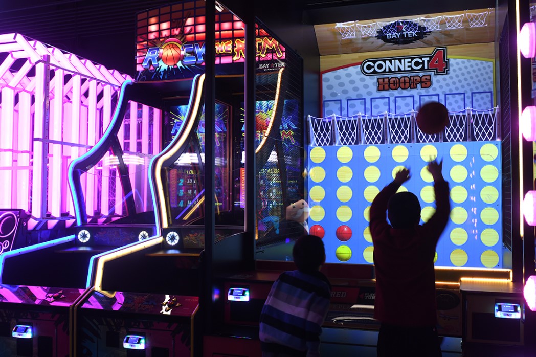 A boy plays a basketball arcade game in a dark arcade room at Arena Sports’ new family entertainment center in Issaquah, Wash., near Seattle