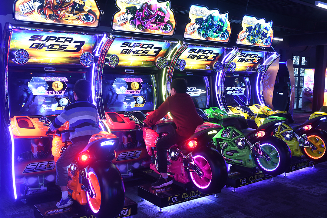 Boys ride on arcade motorcycles playing a game at Arena Sports’ new family entertainment center in Issaquah, Wash., near Seattle