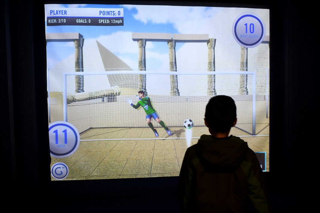 A boy faces a screen playing on one of the sports simulators at Arena Sports’ new family entertainment center in Issaquah, Wash., near Seattle