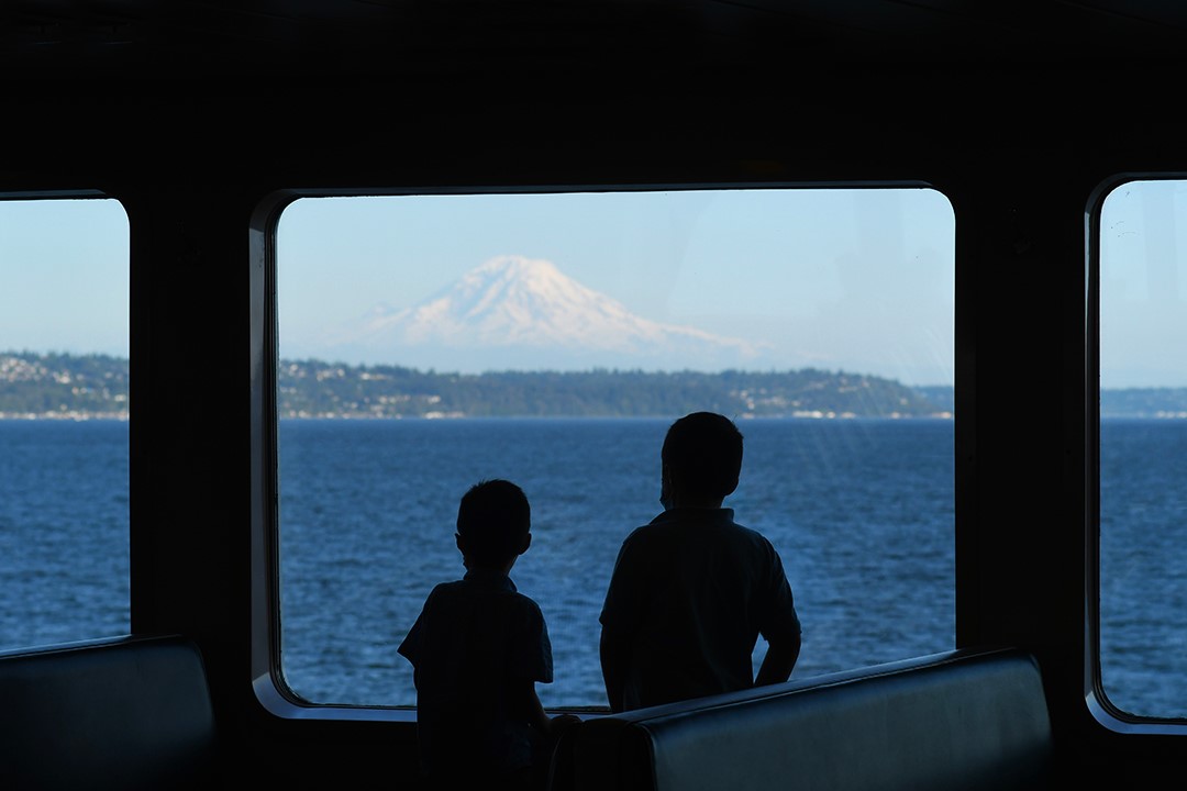 Boys on a Washington State Ferry look out the window at Mount Rainier