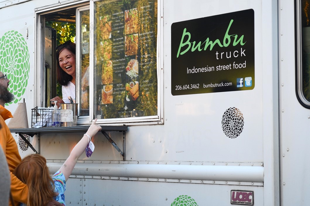 Best Asian restaurants in Seattle include Indonesian food truck Bumbu, a family points at the menu to order at the truck parked at the Queen Anne Farmers Market