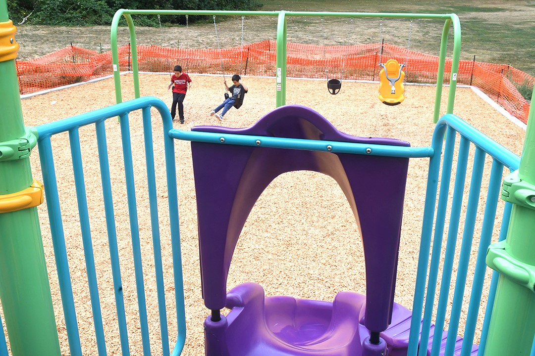 Looking down at the swing set of four swings from the top of the twisty purple slide at Cascade Park in Renton new playground