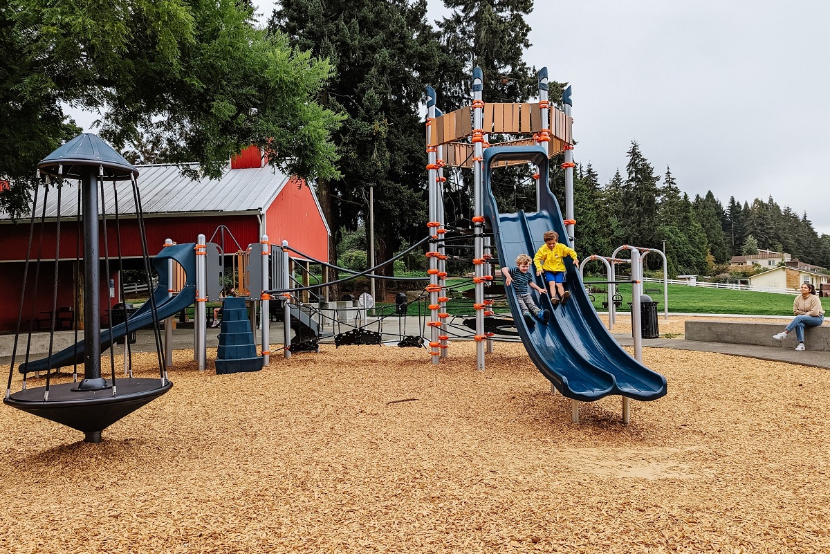 Kids on one of two double slides at Chestnut Ridge Park’s new playground near Seattle