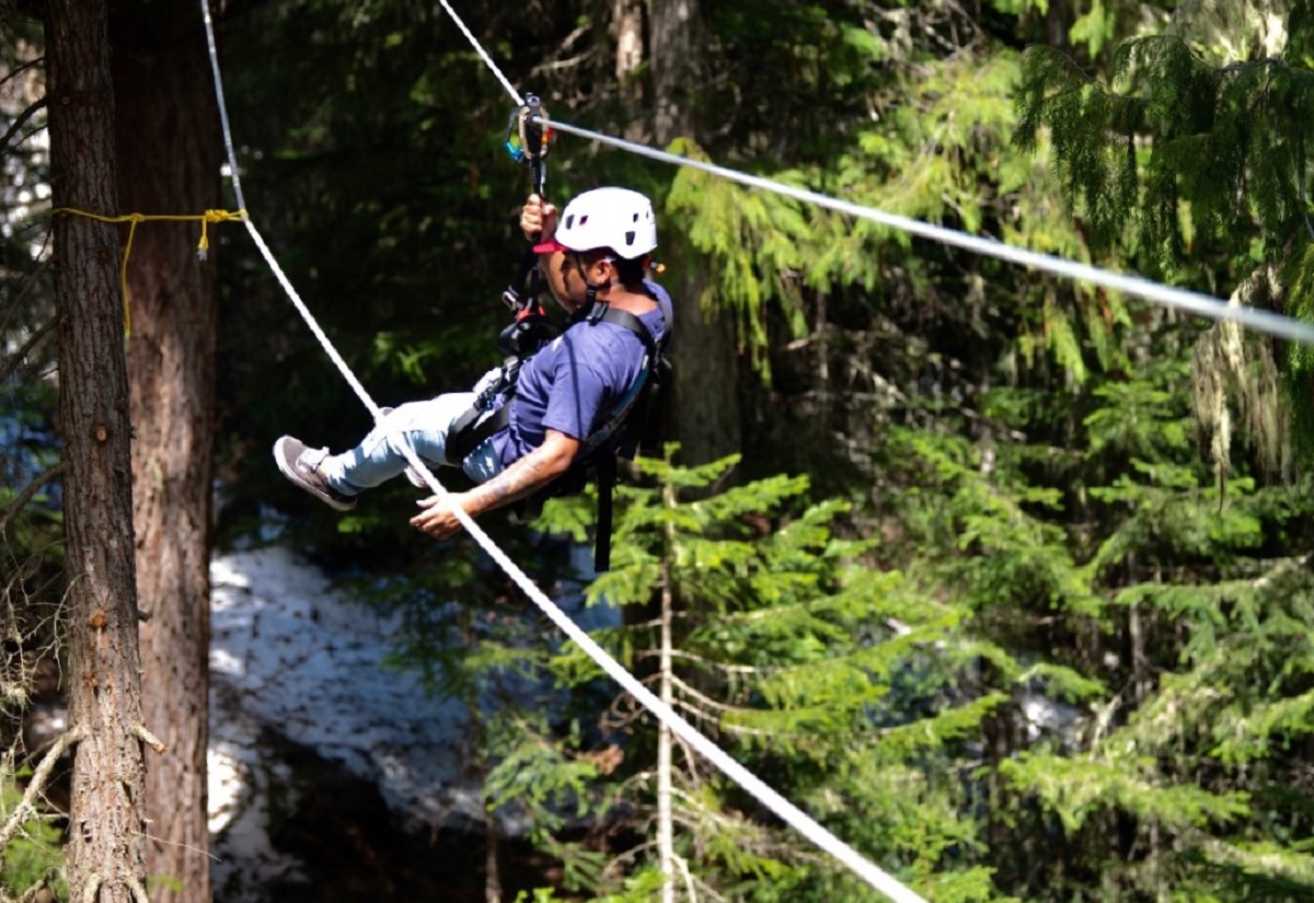 A teenage boy rides the zipline on Crystal Mountain's Flying Raven Adventure Course among summer activities at the ski area