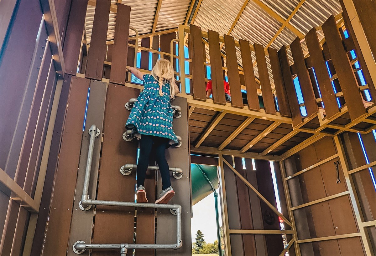 A girl climbs inside the play barn at the recently opened farm-themed playground at Edgewood Community Park
