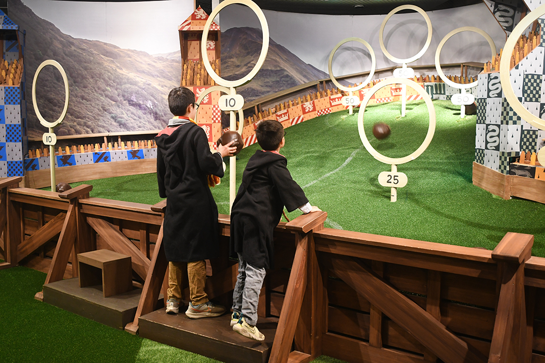 At Harry Potter: Magic at Play in Seattle boys play a Quidditch game throwing quaffles through hoops