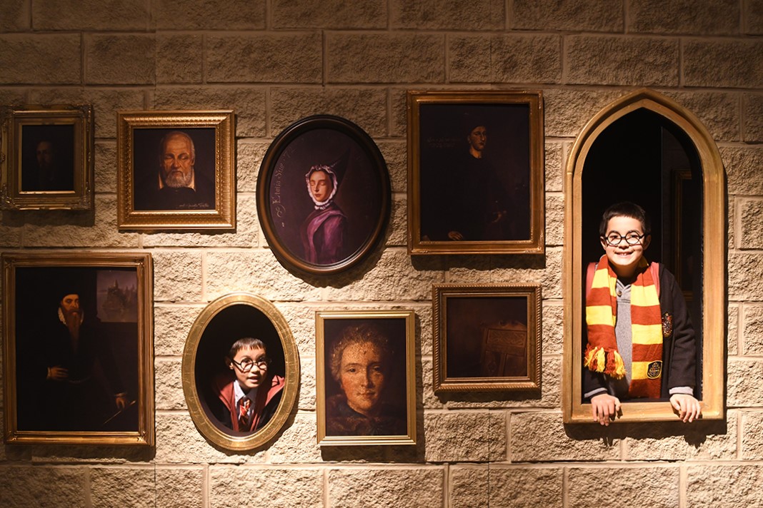At Harry Potter: Magic at Play in Seattle kids peer through the frames on the portrait wall