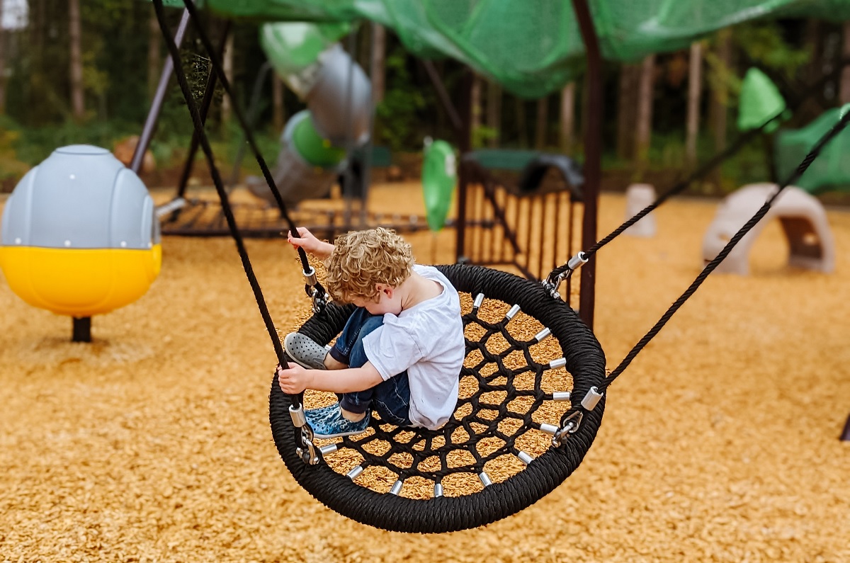 A young boy swings on a disc net swing at Hawks Landing a new playground in Bonney Lake