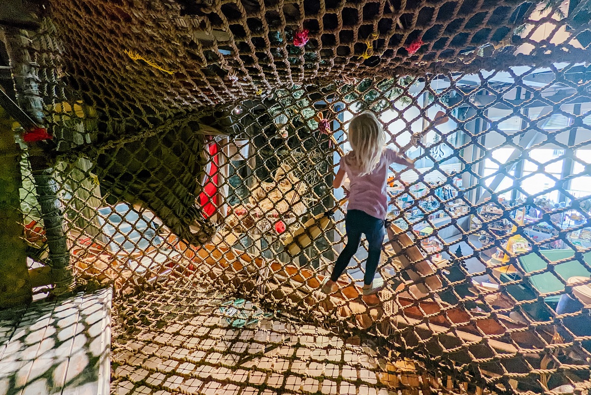 A child visitor to Imagine Children's Museum's new expansion area climbs in a the treehouse rope climber