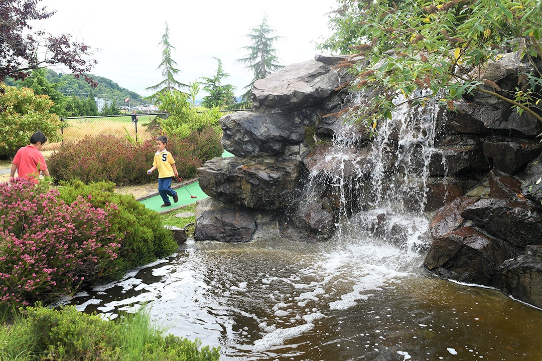 Young boys play mini golf at Interbay Gold Course in Seattle they’re taking shots alongside a waterfall feature