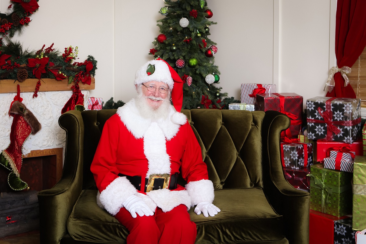 Santa at Kent Station sits in a green chair, ready to pose with your family for holiday photos
