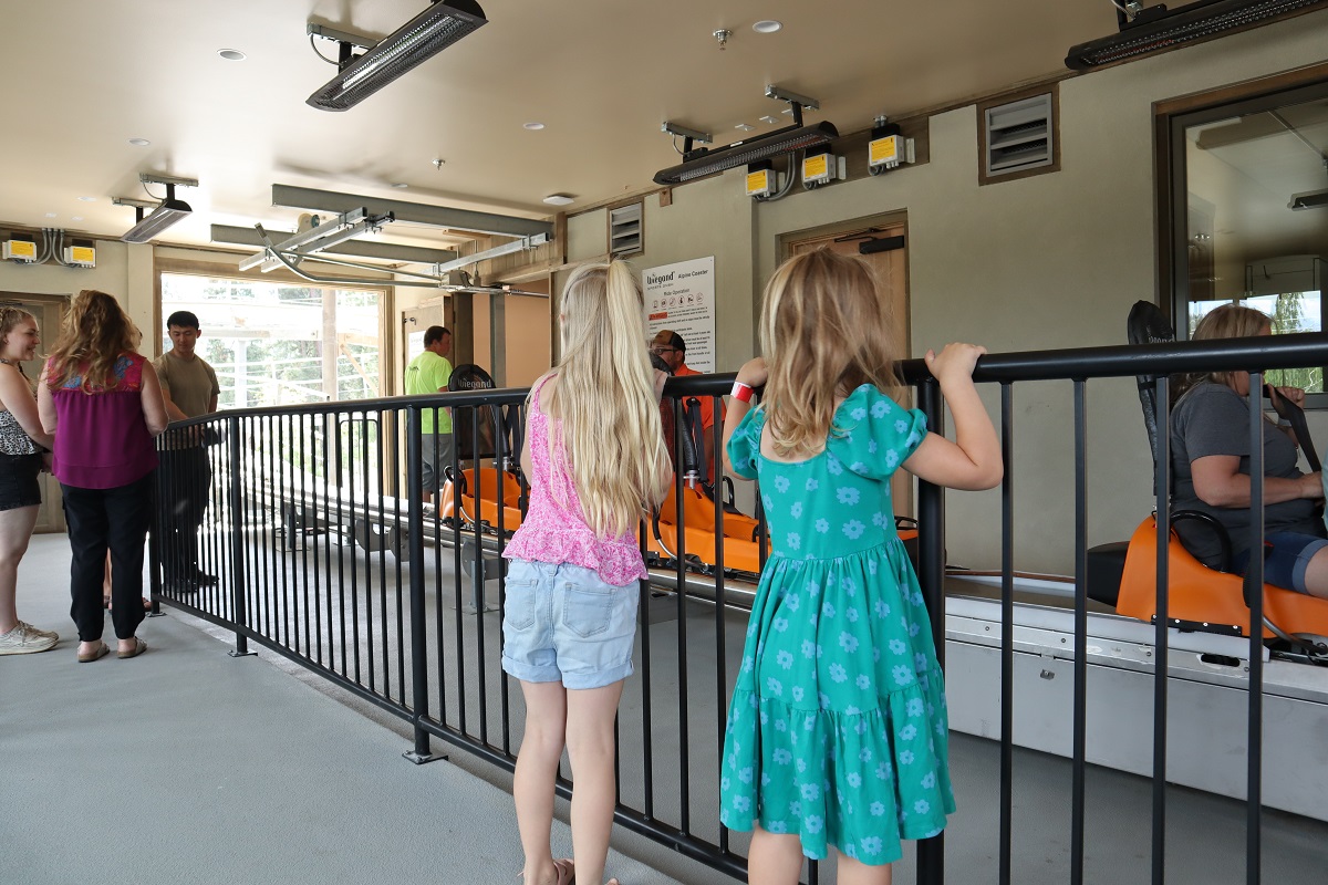 Two girls peer over a railing waiting their turn to board the orange toboggans for the alpine coaster at the newly opened Leavenworth Adventure Park